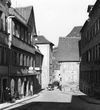 Blick aus Richtung Westen entlang der Heimbacher Gasse; gut sichtbar ist der gefährliche Engpass zwischen „Ritter“ und dem gegenüber liegenden Haus Mauerstraße 1 (frühere Brückenapotheke), durch den gerade ein Auto fährt. Undat., um 1928-1934. Fotograf unbekannt (StadtA Schwäb. Hall DIG 05780, Original: Ivo Lavetti / www.nostalgus.de, alle Rechte vorbehalten)