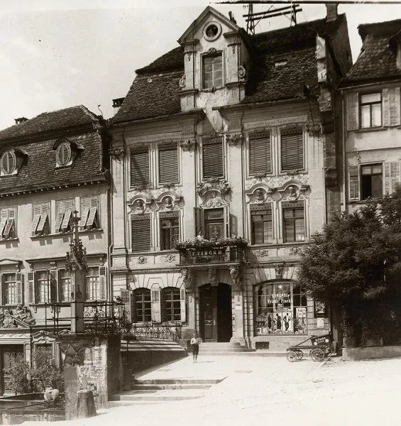 Das Haus um 1919. Eines der angeklebten Plakate am Pranger wirbt für den im Haller „Tonbild-Theater“ gezeigten Film „Das Recht auf Glück“, der 1919 in die Kinos kam. Fotograf unbekannt, evtl. Otto Finckh (StadtA Schwäb. Hall FS 15066)