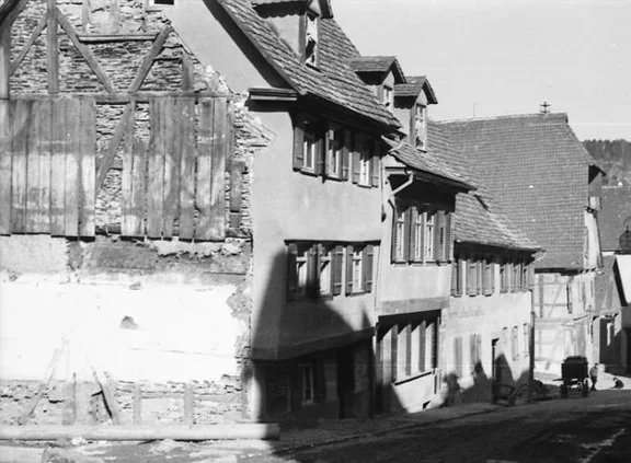 Blick aus Richtung Westen auf die 1933 für den Bau der Johanniterstraße abgerissenen Häuserzeile Heimbacher Gasse 20-24, Nr. 22 ist das mittlere der drei Häuser. Das etwas zurückgesetzte „Wildbad“ (Nr. 18) ist aus diesem Blickwinkel nicht erkennbar - oder es ist bereits abgebrochen. Undat., um 1932-1933. Fotograf unbekannt (StadtA Schwäb. Hall DIG 05909, Original: Ivo Lavetti / www.nostalgus.de, alle Rechte vorbehalten)